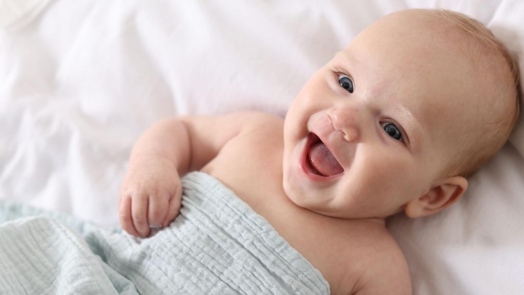 bebé tumbado en la cama y sonriendo